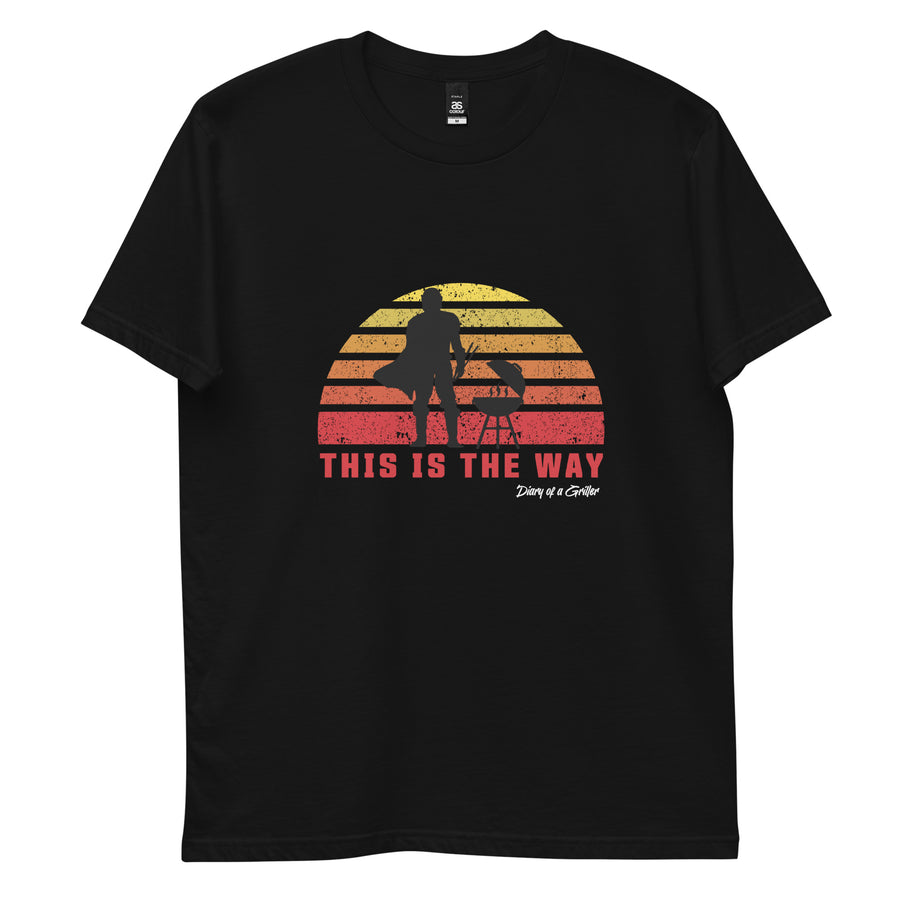 Front of the black tee laid flat, a griller silhouetted against a banded orange sunset above the words THIS IS THE WAY