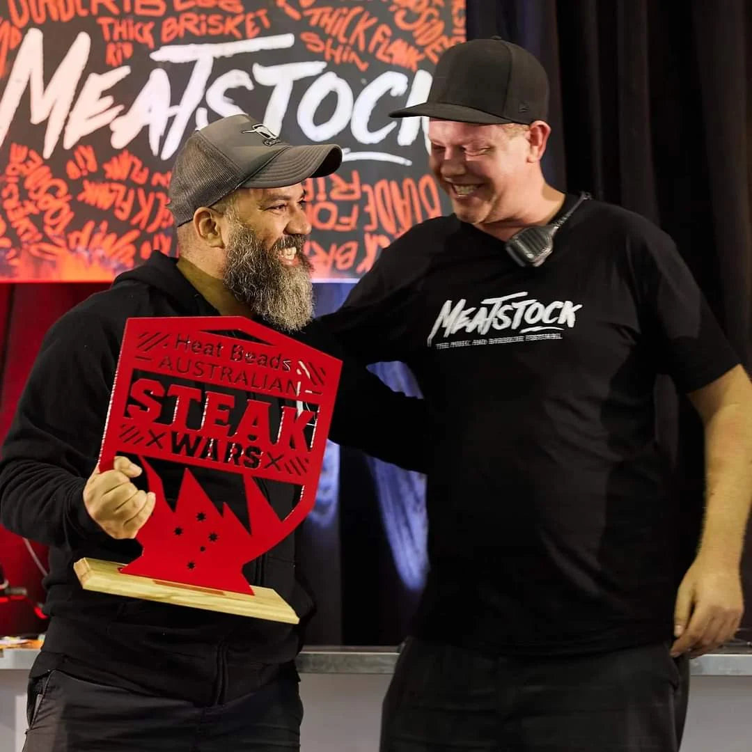 Adriano Andrade holding an Australian Steak Wars trophy beside another participant at Meatstock