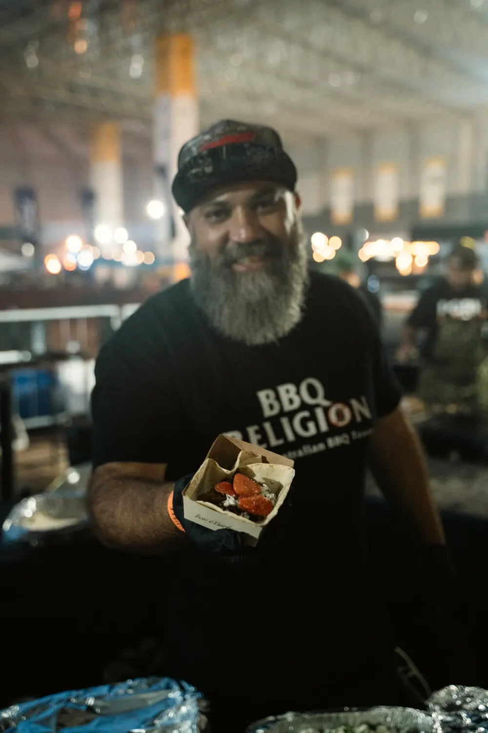 Adriano Andrade in a BBQ Religion tee, serving at a barbecue event